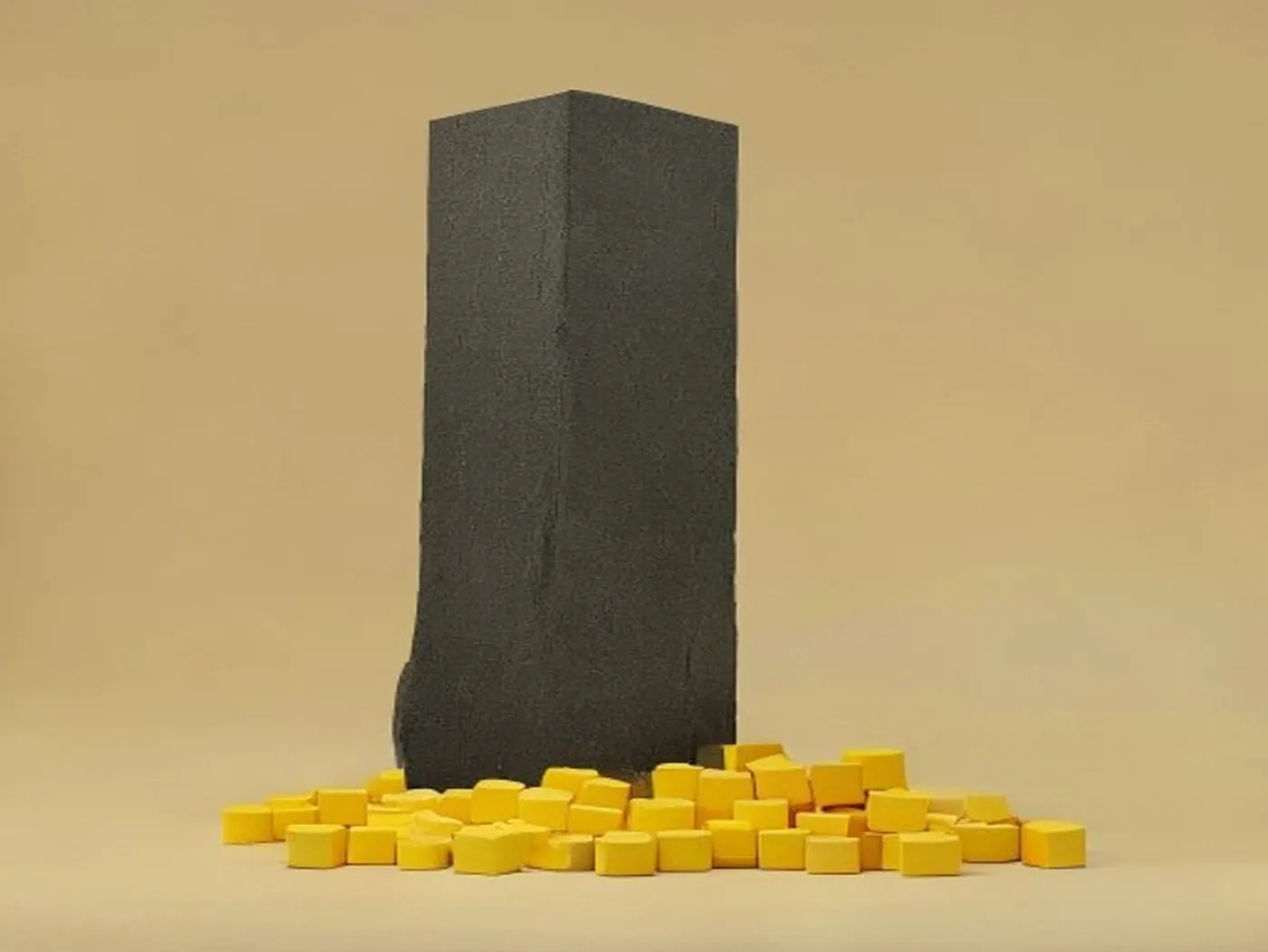Un bloc sombre assemblé debout, à côté d'un tas désordonné de petits cubes jaunes